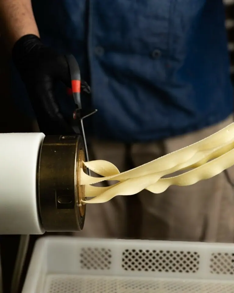 Fresh pasta dough being rolled through a machine in the Stellina kitchen