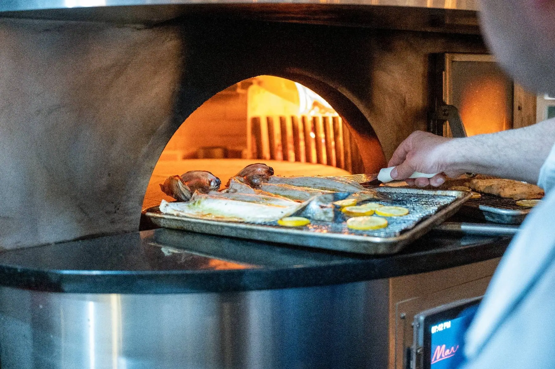 Whole fish and lemon on a tray going into the wood-fired oven at Stellina